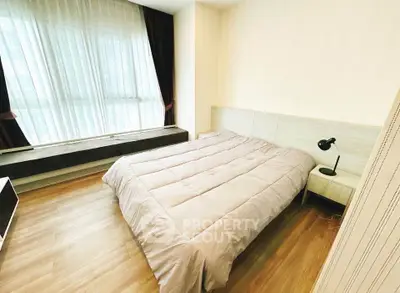 Spacious bedroom with modern decor and large window for natural light