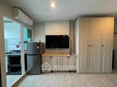 Modern living room with sleek cabinetry and large TV, adjacent to a stylish kitchen area.