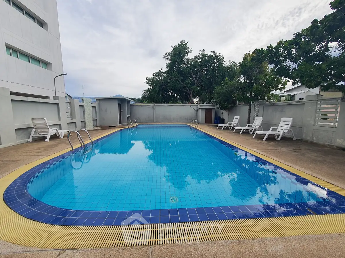 Inviting outdoor pool area with lounge chairs and lush greenery, perfect for relaxation and leisure.
