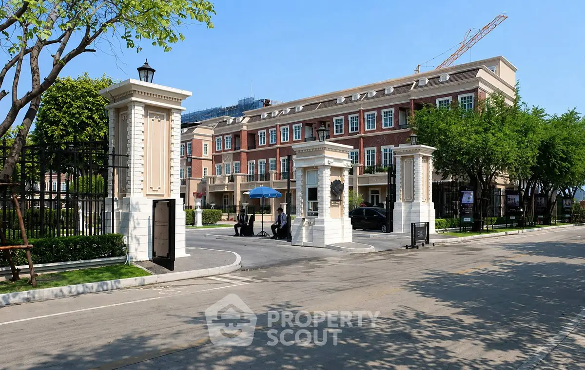 Elegant gated entrance to luxury residential complex with classic architecture and lush greenery.