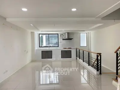 Spacious modern kitchen with sleek design and open layout, featuring large windows and glossy tiled floors.