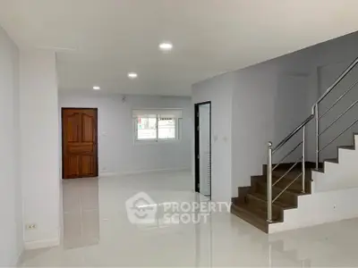 Spacious modern living room with sleek staircase and glossy flooring, perfect for contemporary living.