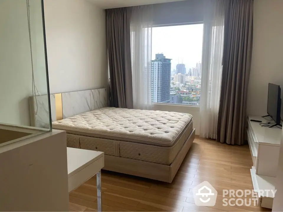 Modern bedroom with city view, featuring a comfortable bed and sleek furnishings.