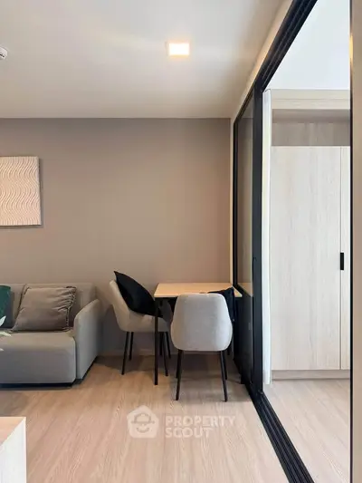 Modern living room with cozy seating and dining area, featuring sleek furniture and natural light.