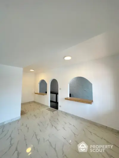 Spacious interior with elegant arches and marble flooring, perfect for modern living.