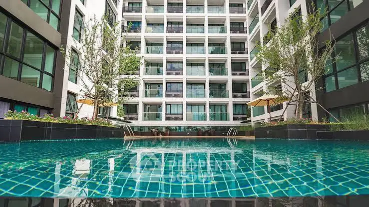 Modern apartment building with a luxurious swimming pool and lush greenery.