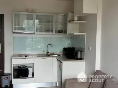 Modern compact kitchen with sleek cabinets and appliances in a cozy apartment setting.