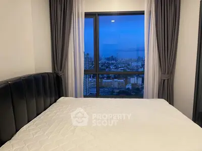 Modern bedroom with stunning city view from large window.