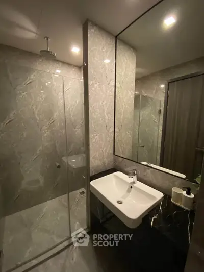 Modern bathroom with sleek design featuring a glass shower and elegant sink.