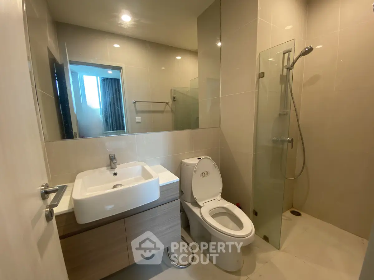 Modern bathroom with sleek fixtures and glass shower in contemporary apartment.