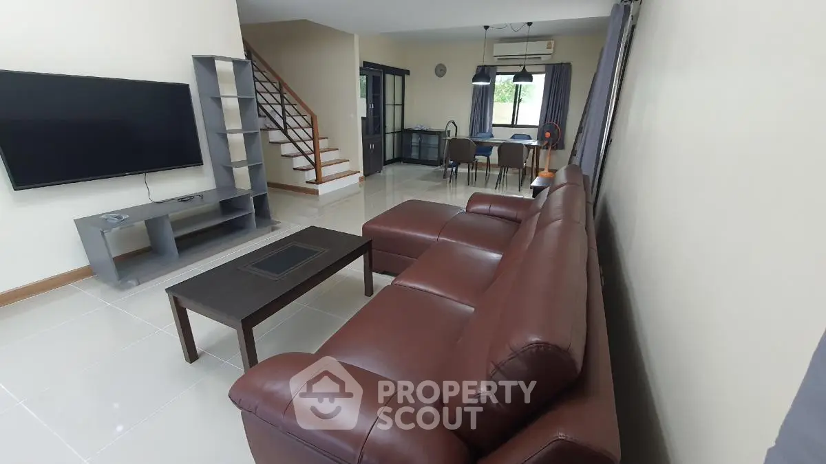 Spacious modern living room with leather sofa and large TV, open layout design.
