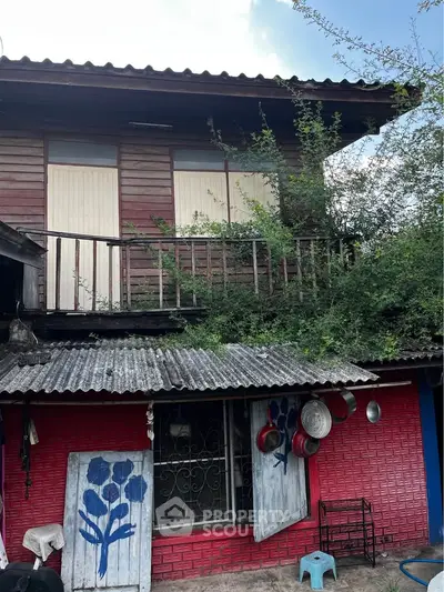 Charming rustic two-story wooden house with vibrant red brick facade and lush greenery.