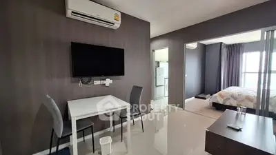Modern apartment interior with dining area, wall-mounted TV, and bedroom view.