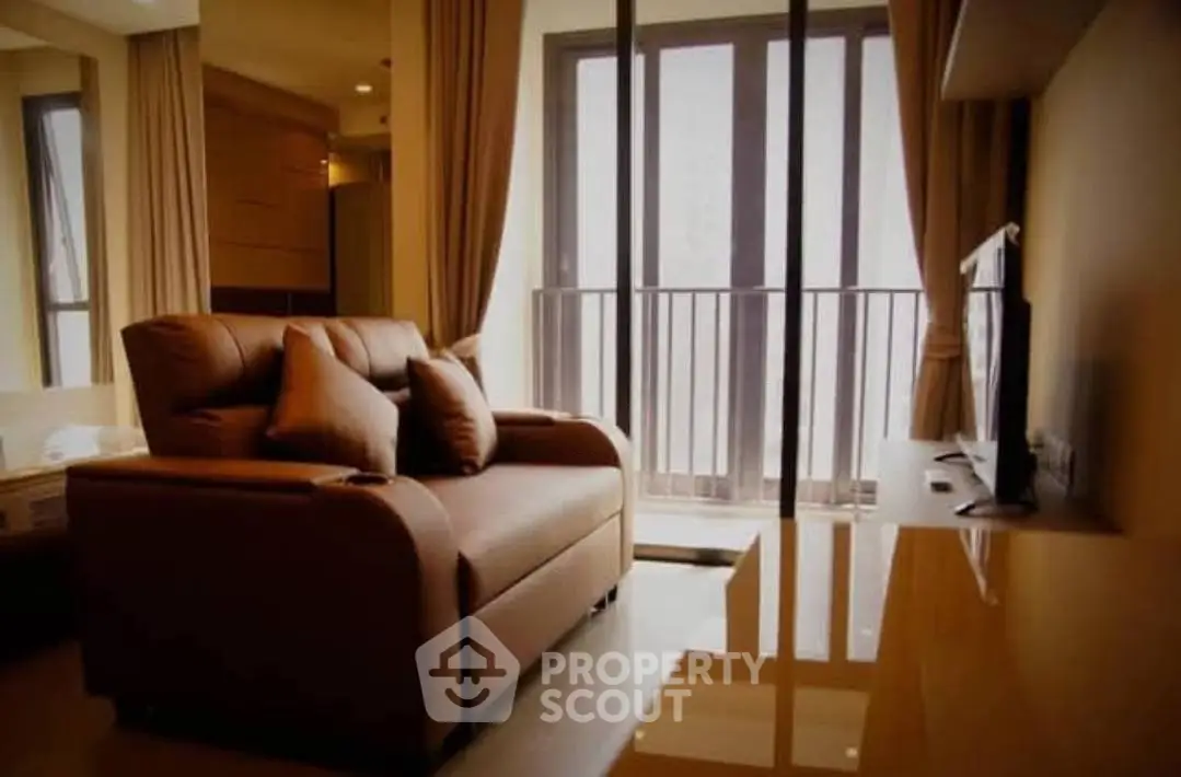 Cozy living room with modern sofa and large windows offering natural light and balcony access.