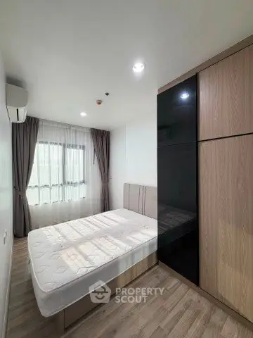 Modern bedroom with large window and built-in wardrobe in a stylish apartment.