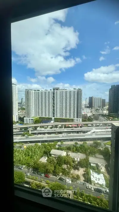 Stunning cityscape view from high-rise apartment window with clear blue skies.