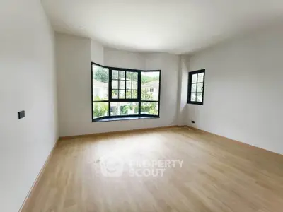 Spacious empty room with large windows and wooden flooring, perfect for customization.