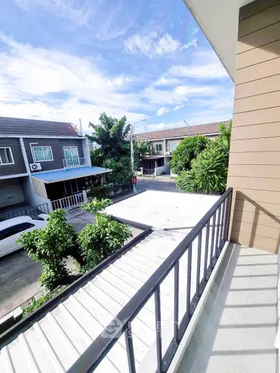 Charming townhouse balcony with street view and lush greenery, perfect for relaxing outdoors.