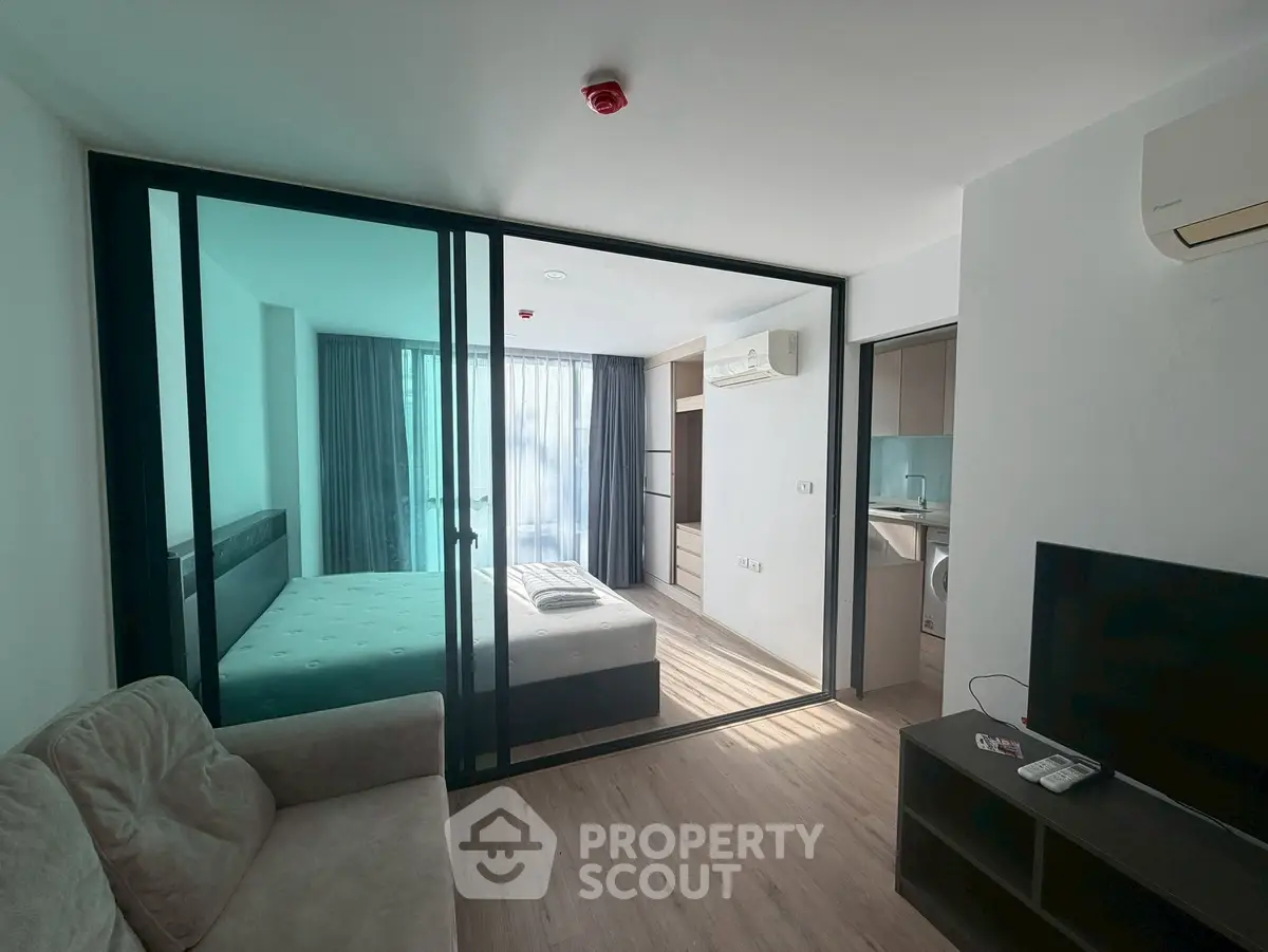 Modern studio apartment with glass partition, cozy living area, and natural light