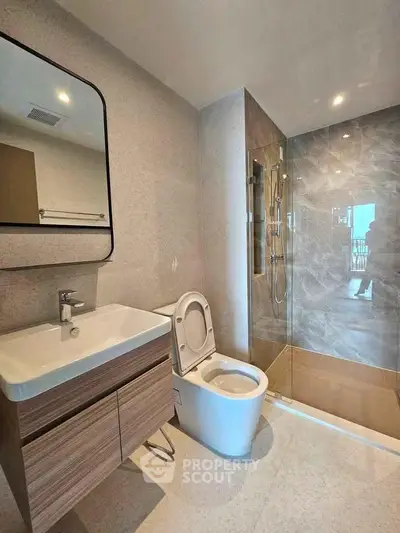 Modern bathroom with sleek fixtures and glass shower enclosure in a stylish apartment.