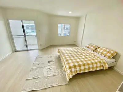 Spacious bedroom with large windows and balcony access, featuring a cozy bed and minimalist decor.