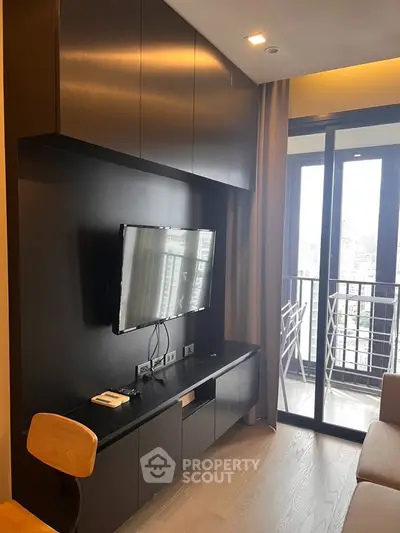 Modern living room with sleek TV setup and balcony view in urban apartment