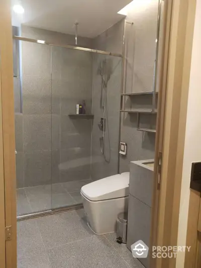 Modern bathroom with a spacious glass-enclosed shower, sleek fixtures, and built-in shelving, offering a blend of functionality and contemporary style.