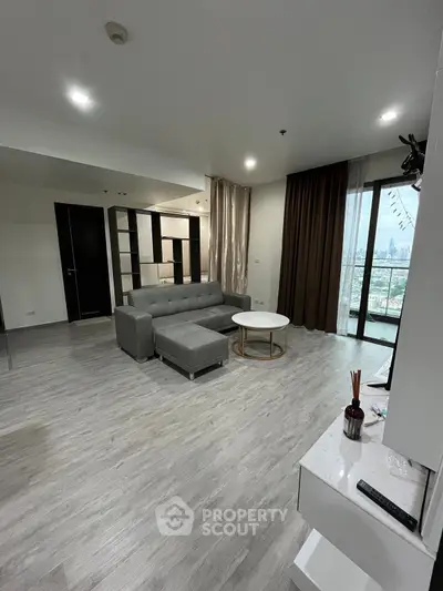 Modern living room with sleek gray sofa and city view balcony