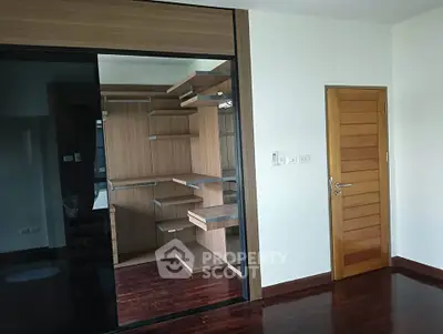 Spacious modern bedroom with sleek wooden flooring and built-in closet