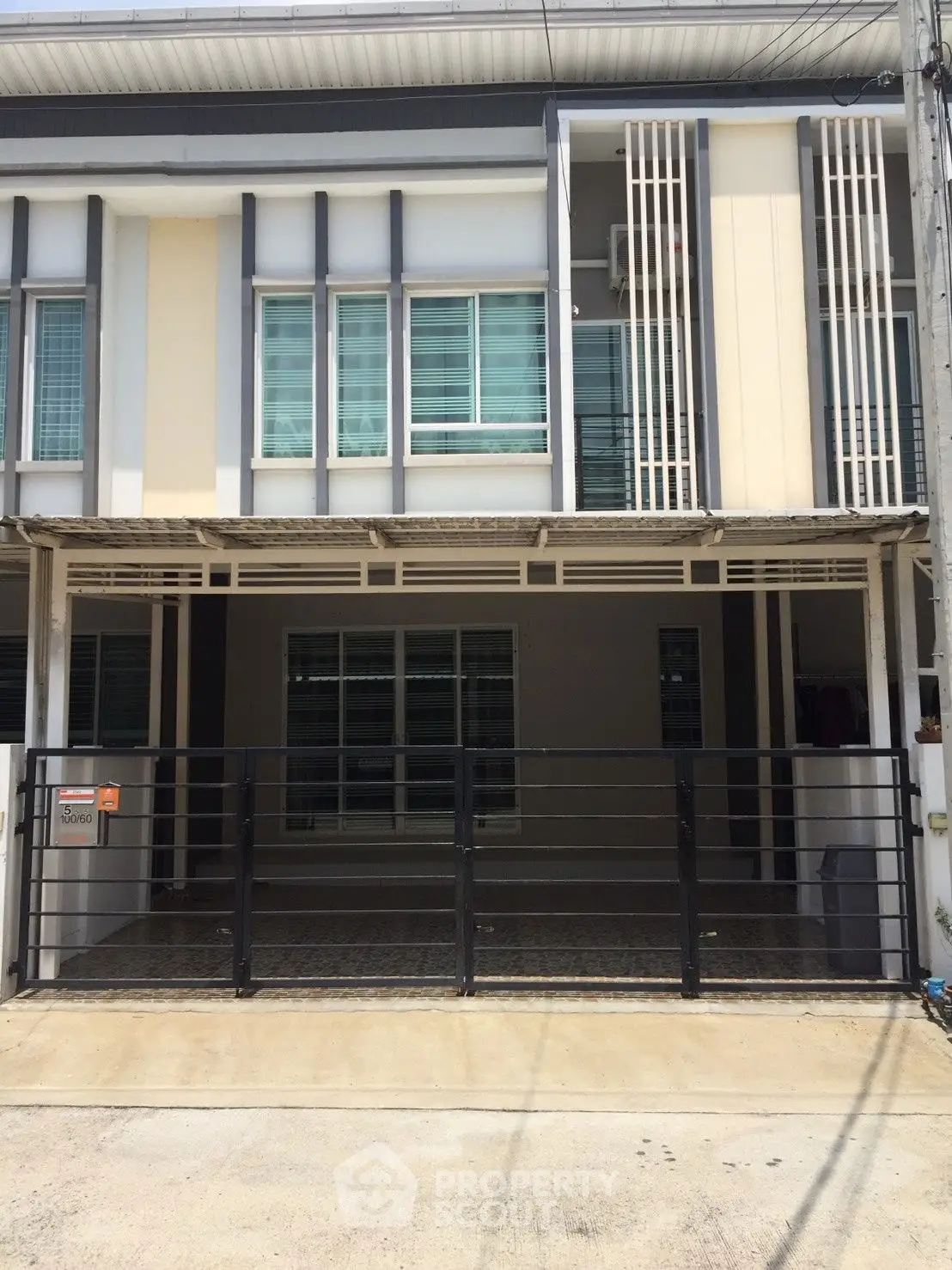 Modern two-story townhouse with gated parking and sleek facade design.