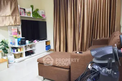 Cozy living room with brown sofa, large TV, and elegant curtains for a comfortable home setting.