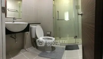 Modern bathroom with glass shower and sleek fixtures in contemporary apartment.
