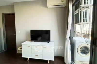 Modern living room with TV, air conditioning, and washing machine near balcony.
