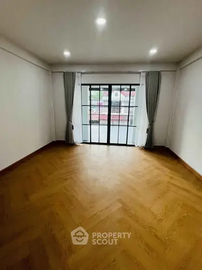 Spacious empty room with wooden flooring and large window view