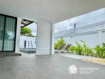 Modern outdoor patio with sleek tiles and lush greenery, perfect for relaxation and leisure.