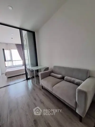 Modern apartment interior with cozy living room and bedroom, featuring sleek furniture and natural light.