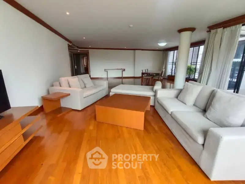 Spacious living room with wooden flooring and modern furniture in a luxury apartment.