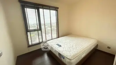 Spacious bedroom with large window and wooden flooring, perfect for natural light lovers.