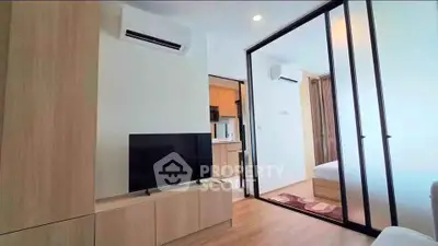 Modern apartment interior with sliding glass doors, TV, and air conditioning, showcasing a cozy living space.
