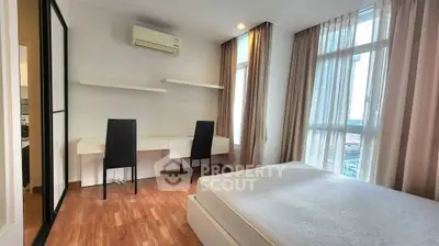 Spacious bedroom with modern furniture and large windows offering natural light.