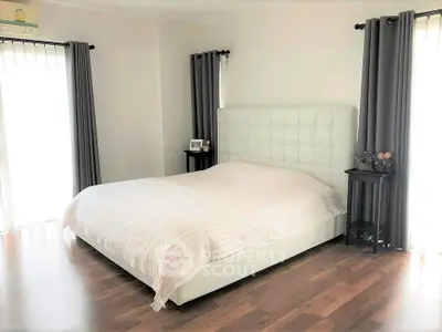 Spacious bedroom with elegant decor and natural light, featuring a large bed and stylish curtains.