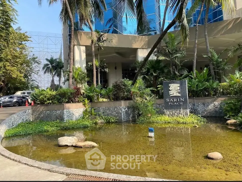 Luxurious building entrance with serene water feature and lush greenery at Sarin Place.