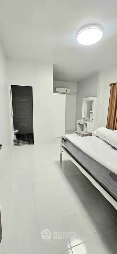 Spacious bedroom with minimalist design and ensuite bathroom in modern apartment.