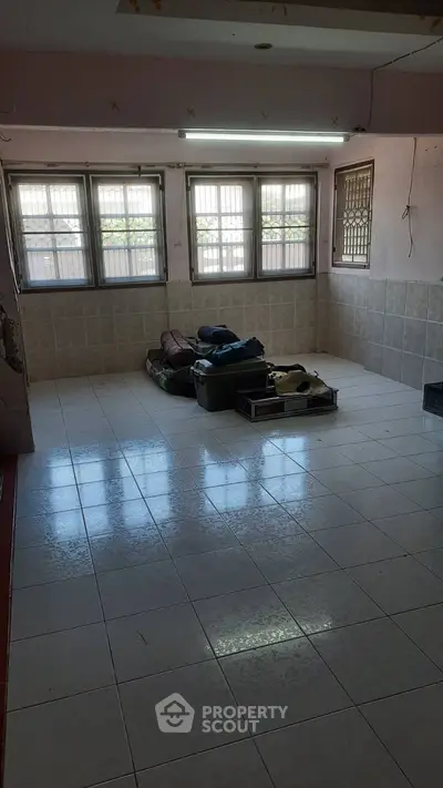 Spacious tiled room with large windows and natural light, ideal for versatile use.