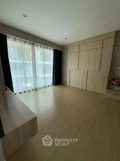 Spacious modern living room with wooden flooring and large windows for natural light.