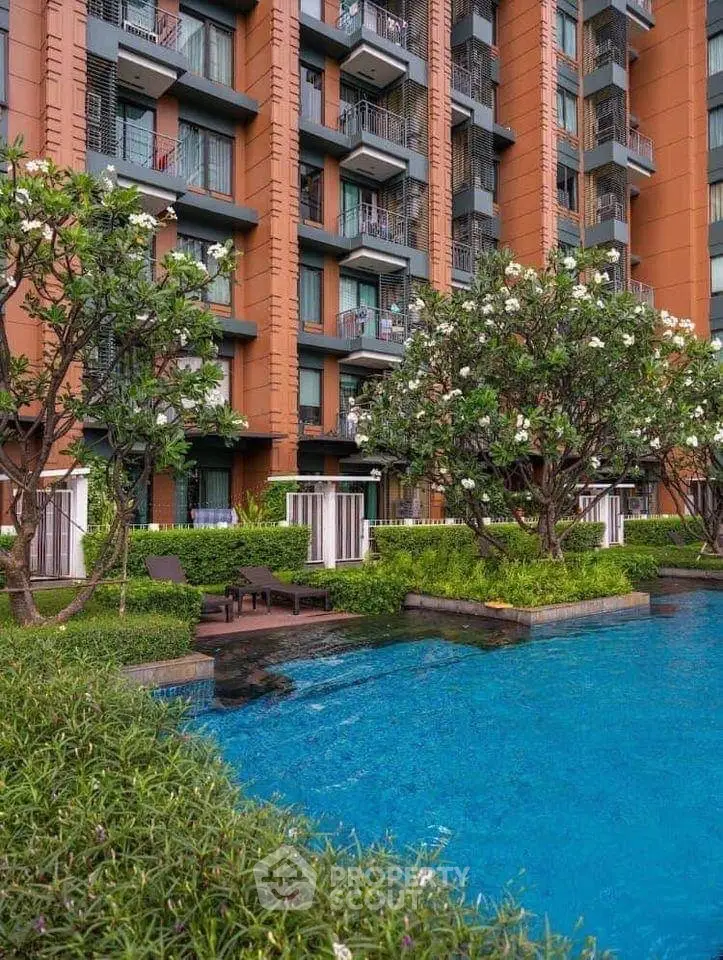 Luxurious apartment building with stunning pool and lush garden view.