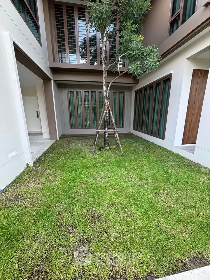 Charming courtyard with lush green lawn and modern architectural design, perfect for relaxation and outdoor gatherings.