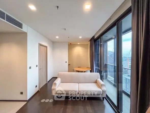 Modern living room with large windows and balcony view in a high-rise apartment.