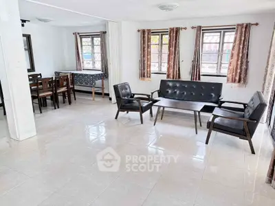 Spacious living room with modern furniture and dining area, featuring large windows for natural light.