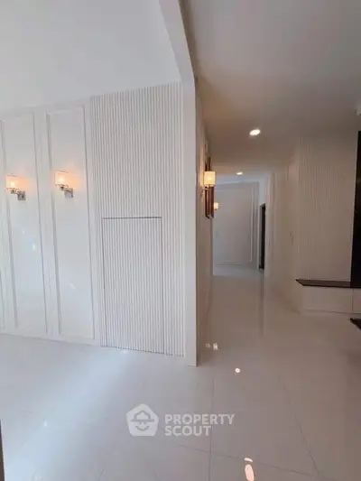 Elegant hallway with modern lighting and sleek white walls in a luxury apartment.
